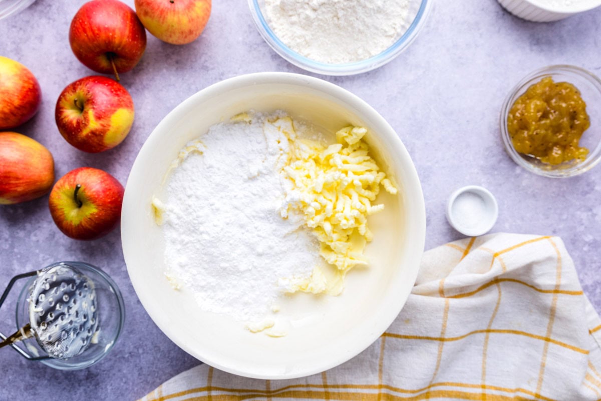 butter and powdered sugar in bowl on counter with ingredients around.