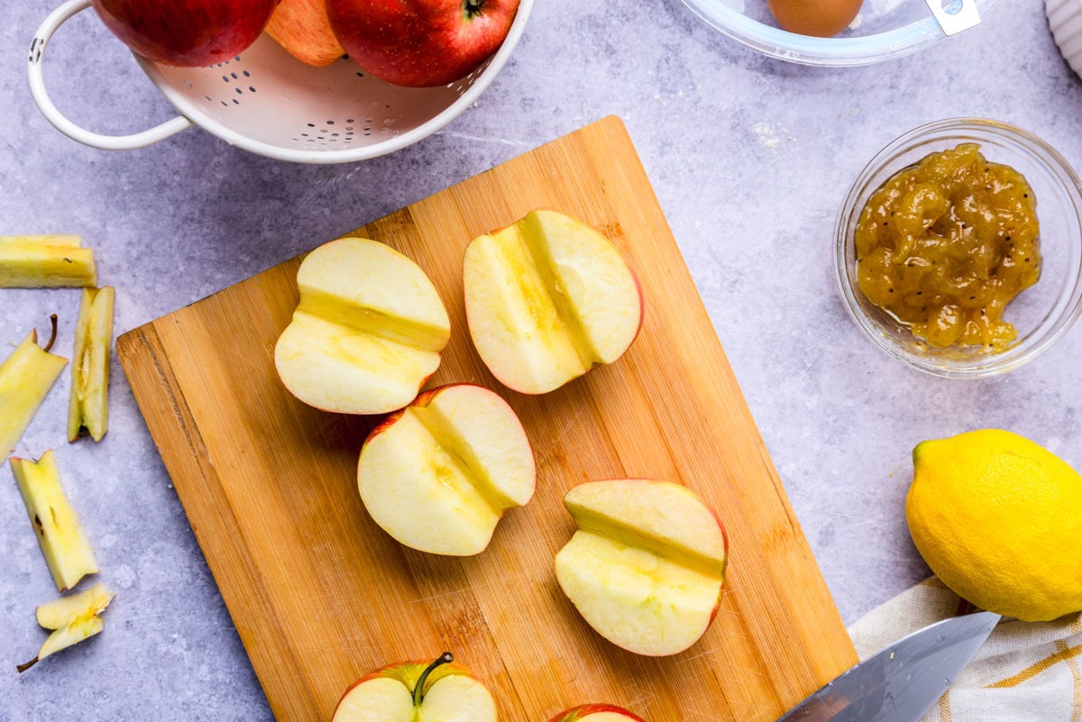 apples cut in half and cored sitting on cutting board.