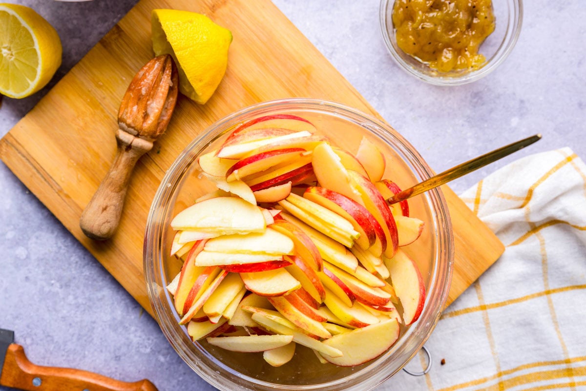 apple slices in bowl covered in lemon juice.