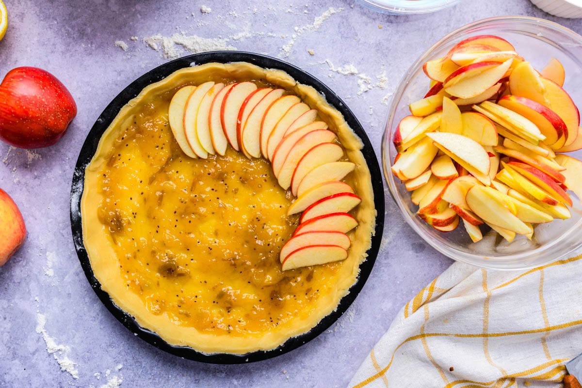 apple slices arranged in pie crust on counter.