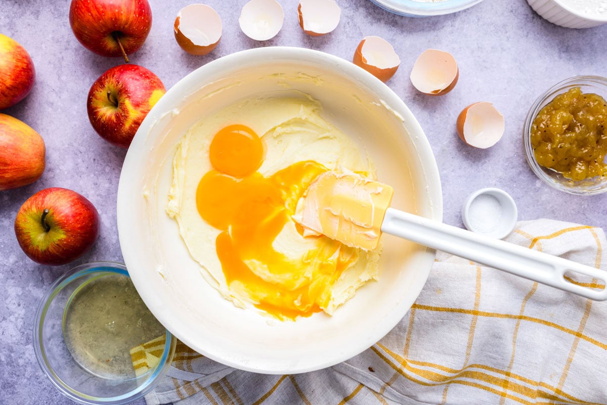 mixing egg yolks into butter and sugar mixture in bowl.