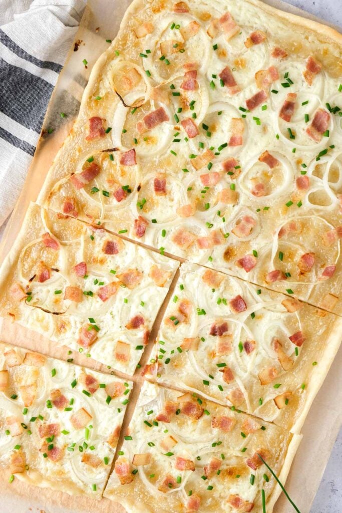 flammkuchen on cutting board cut into pieces.