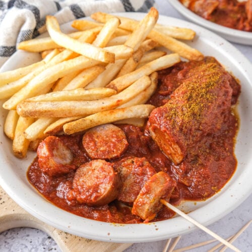 plate of currywurst with fries beside.