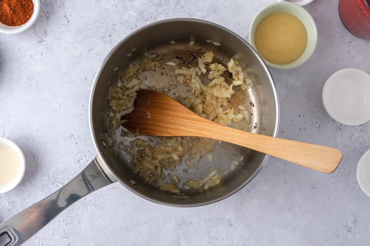 wooden spatula moving onions around pan.