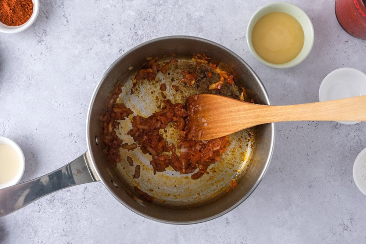 fried onions and tomato paste in pot on counter.