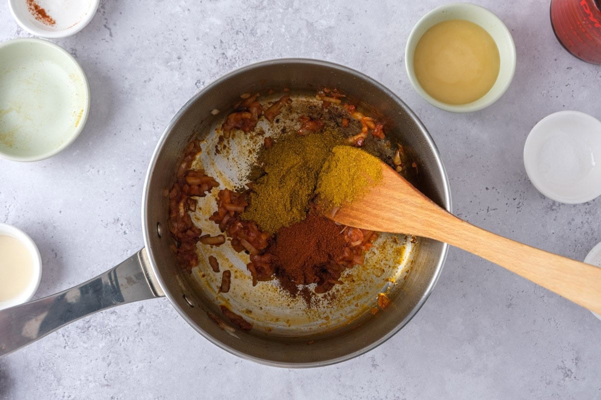spices in pot with wooden spoon stirring on counter.