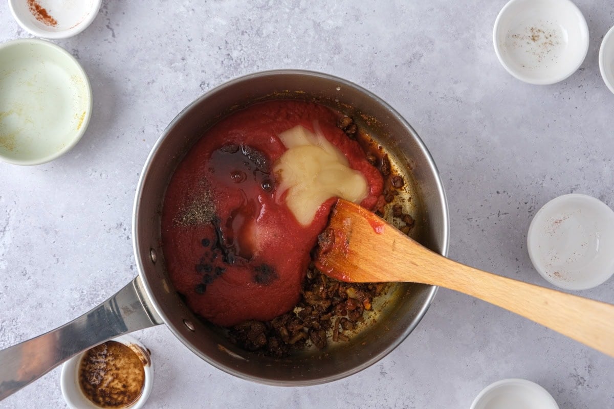 wet ingredients in silver pot with wooden spatula sticking out.