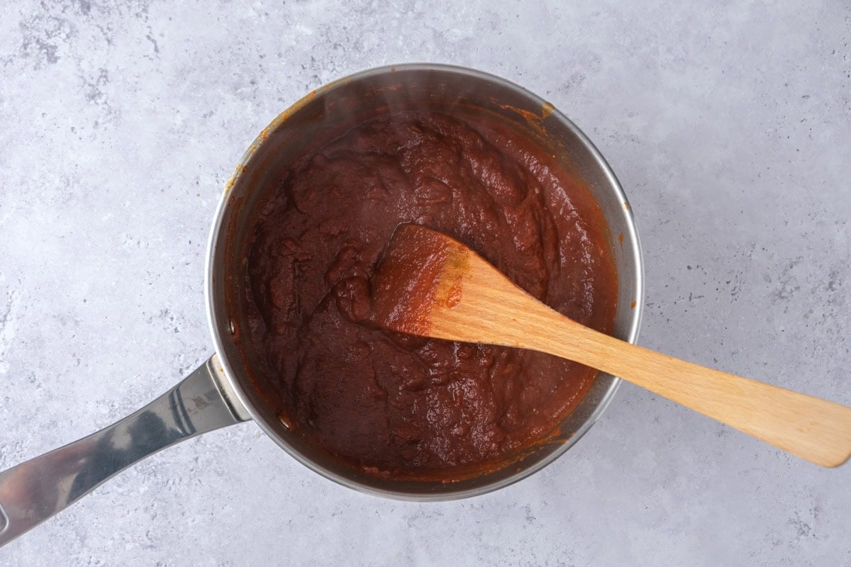 pot of currywurst sauce with wooden spatula in it.
