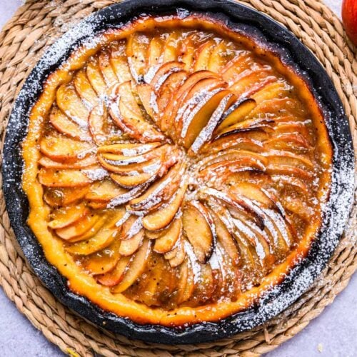 cooked apple crostata on counter with apple beside.
