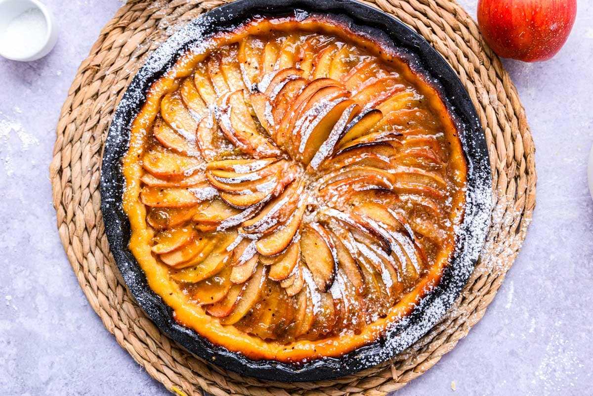 cooked apple crostata on counter with apple beside.