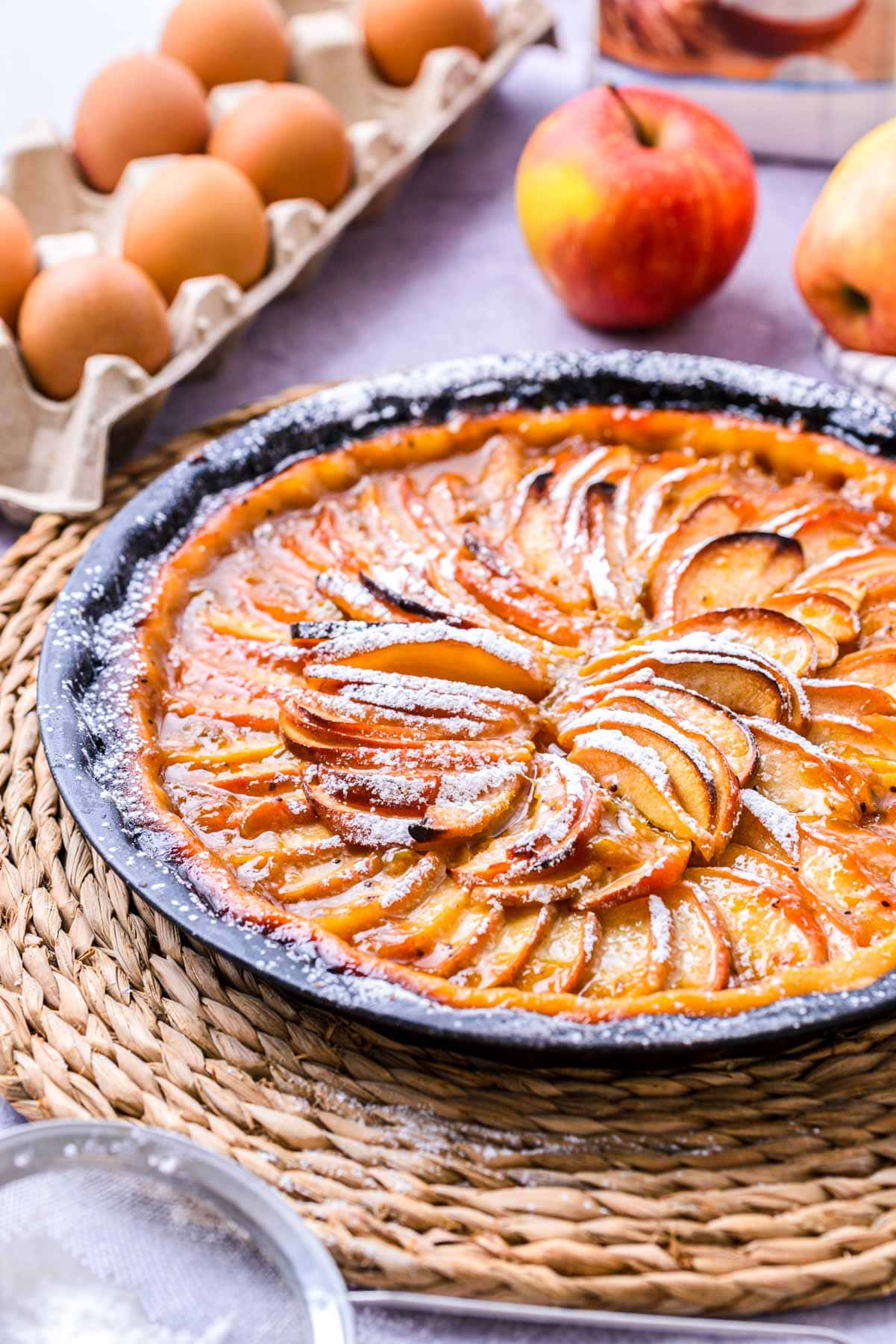 apple crostata in pan on wicker serving platter on counter.