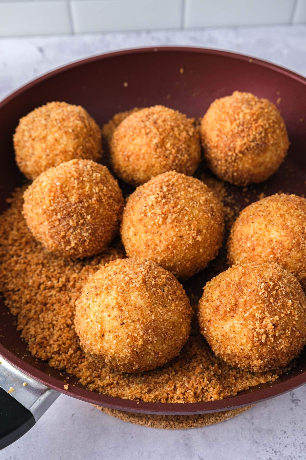 plum dumplings covered in breadcrumbs in frying pan.