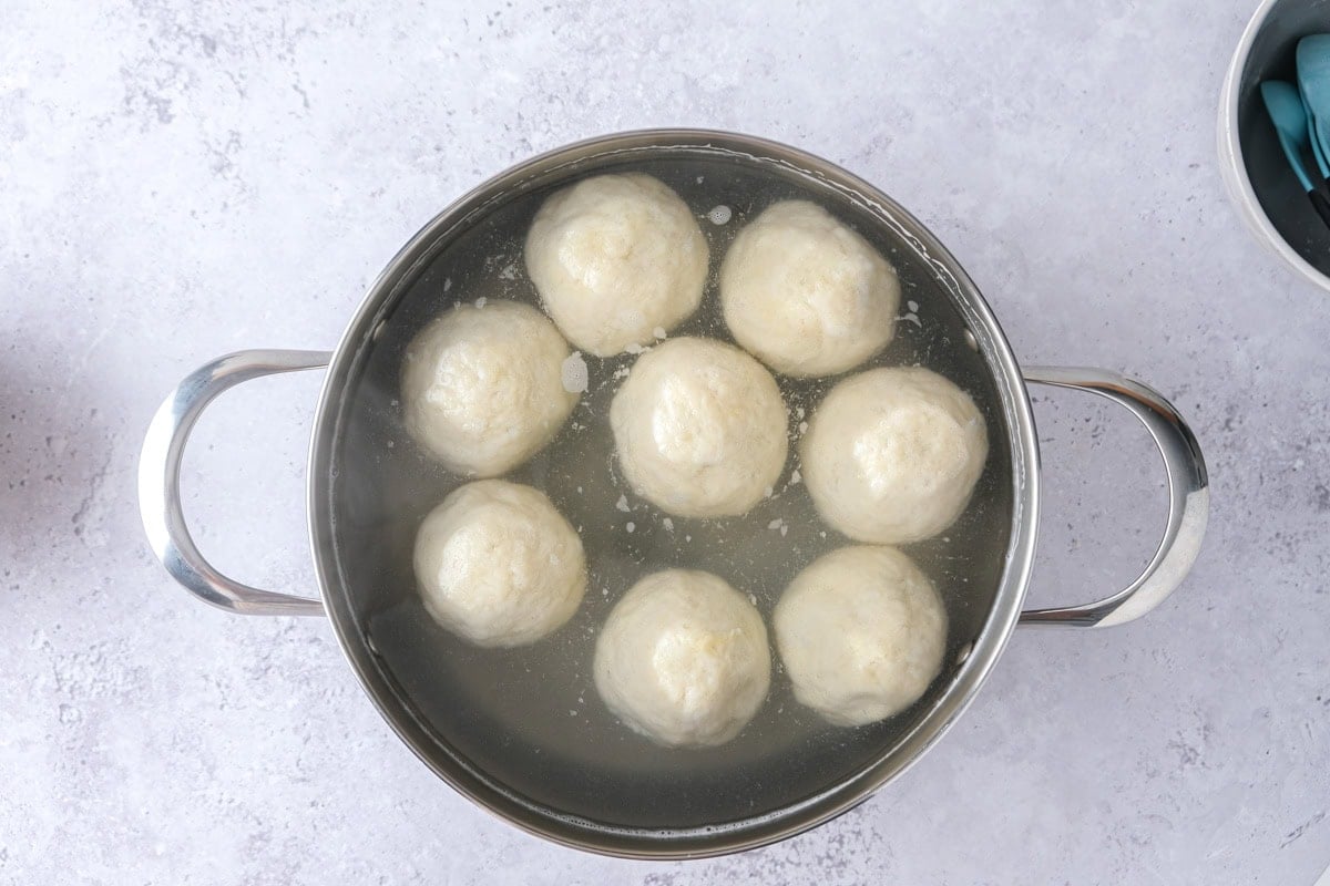 plum dumplings floating in pot of water with counter around.