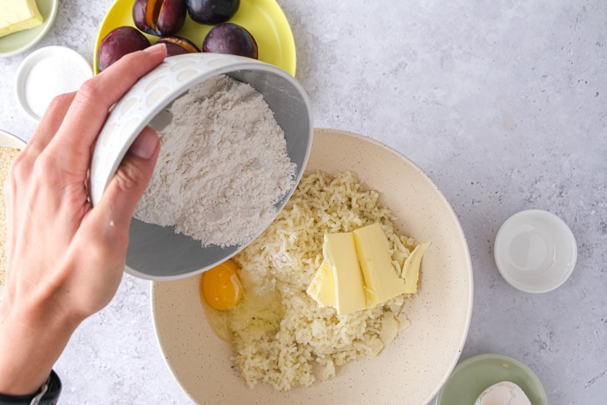 hand pouring flour into bowl of other doiugh ingredients.