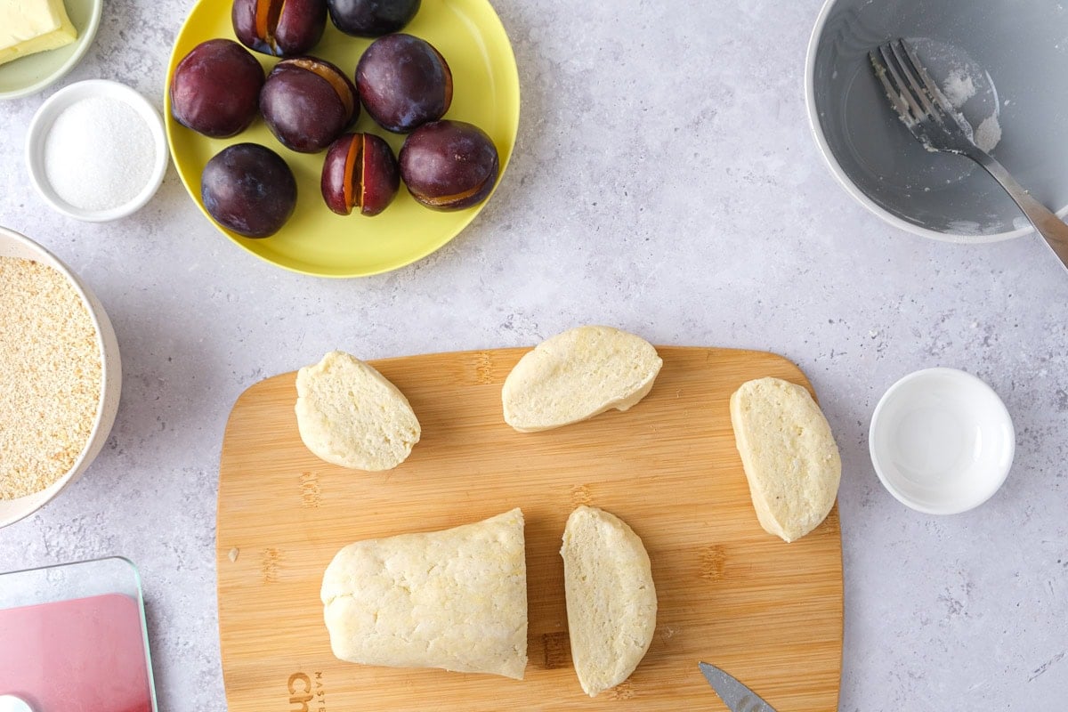 sausage of dough on cutting board cut into pieces.