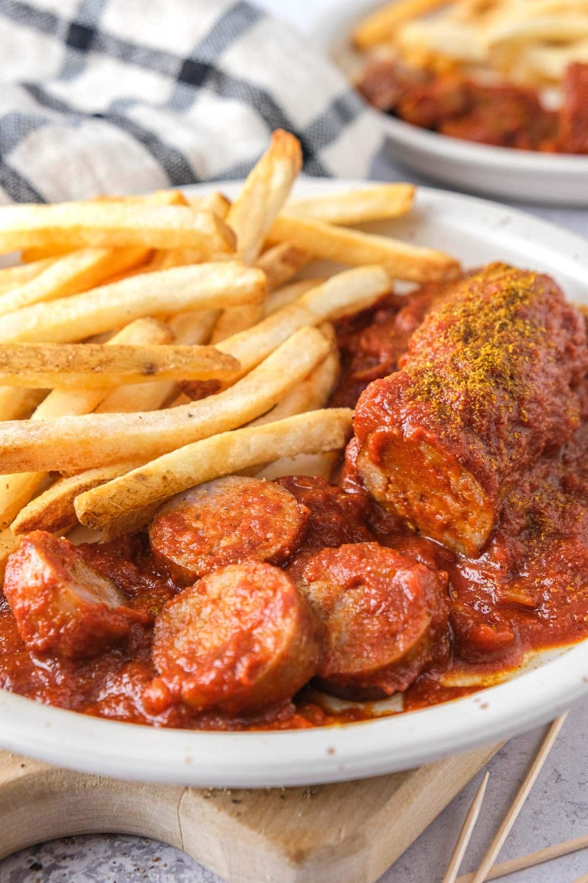sliced currywurst on plate with fries beside.
