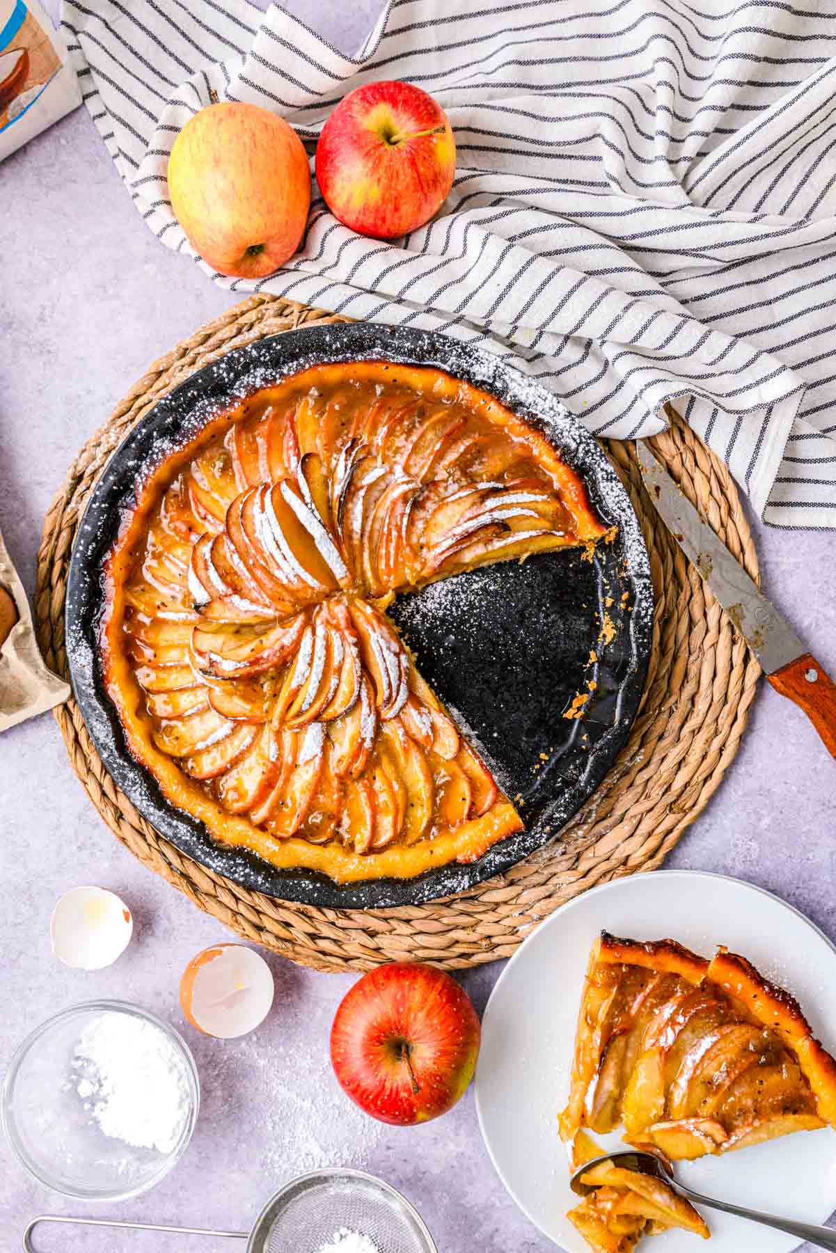 baked apple crostata with slice removed sitting on counter with slice beside on plate.