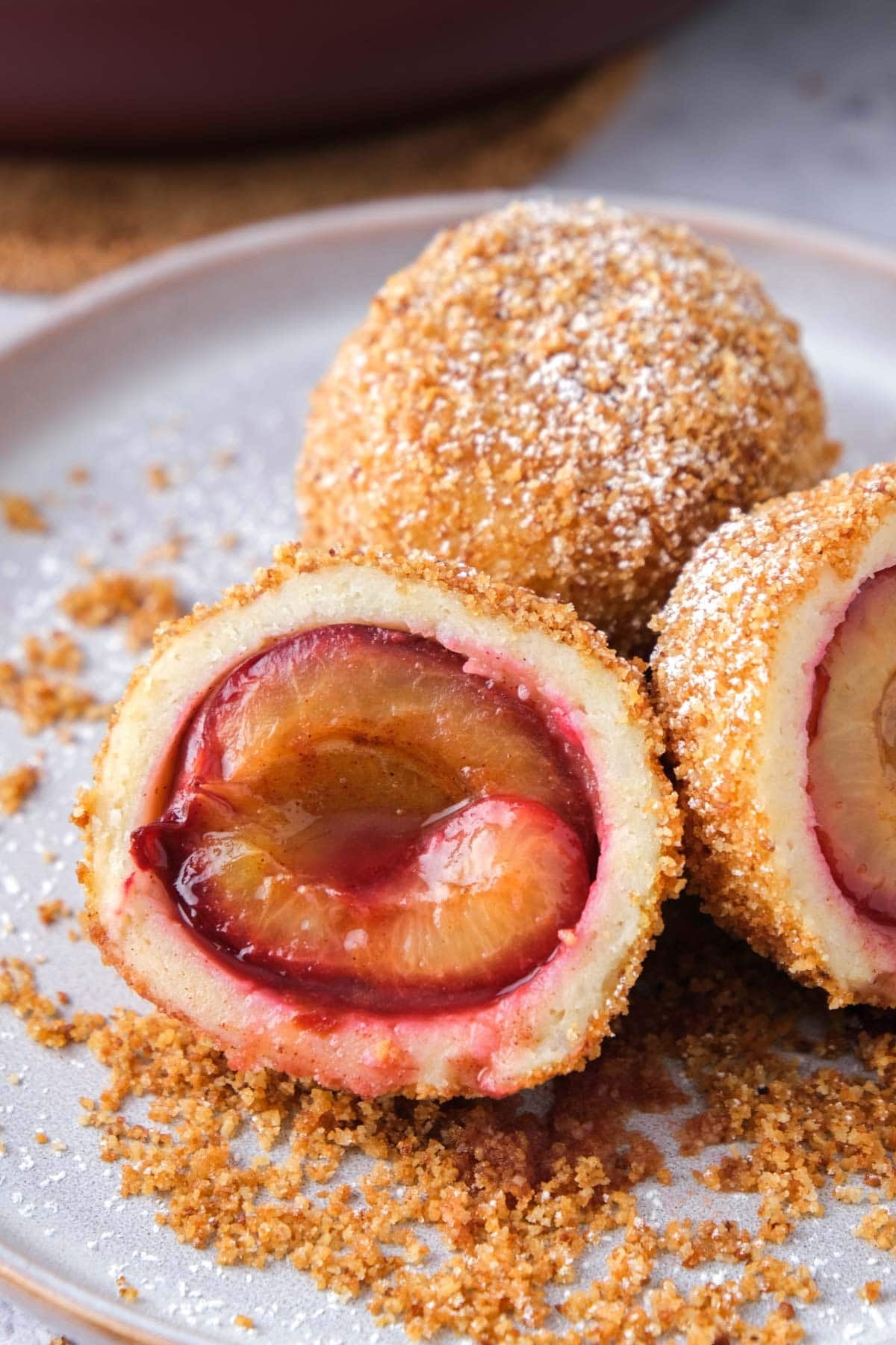 close up of plum dumpling cut in half on plate.