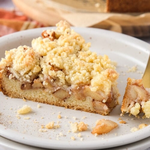 slice of german apple cake on plate with golden fork removing some.