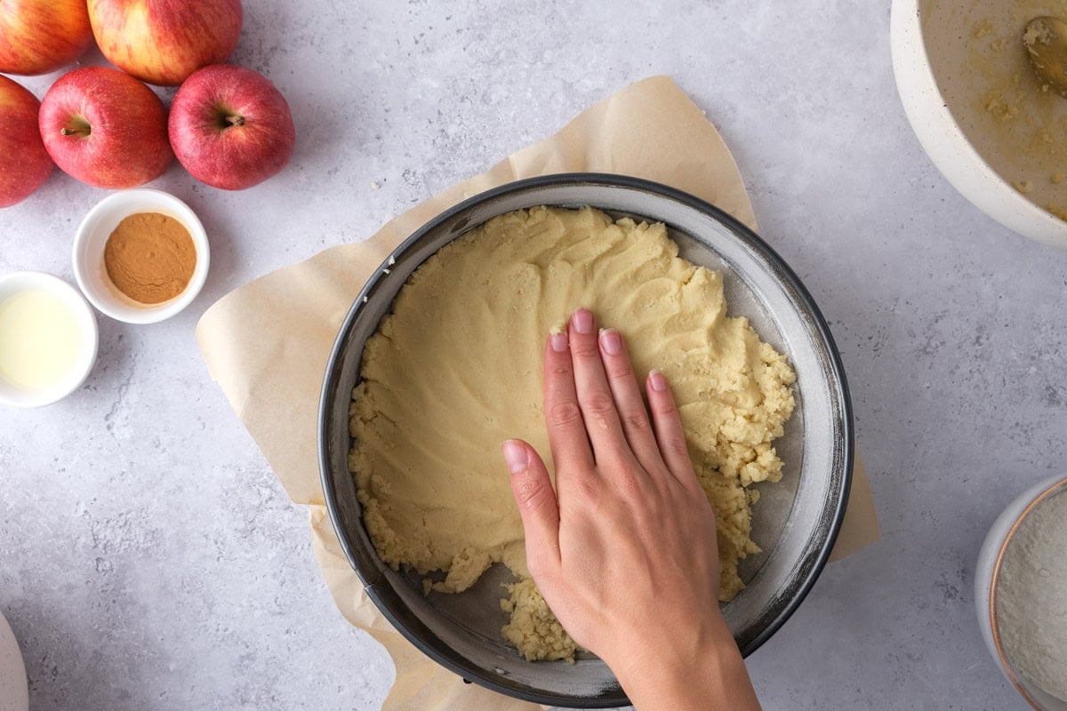 hand forming raw dough into cake form on counter.