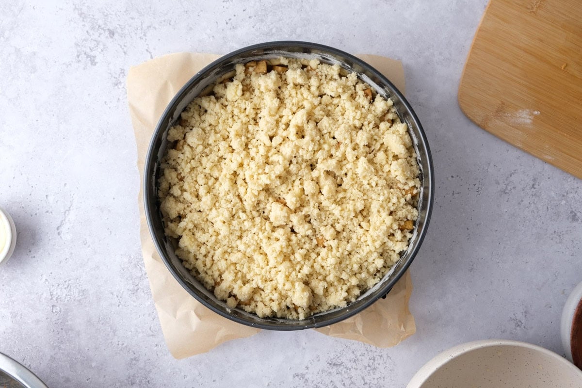 raw german apple cake covered in classic crumbles sitting on counter.